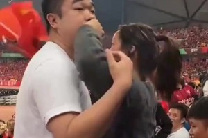 女学生在中国球迷区举起韩国国旗，一旁夫妻俩帮着说好话